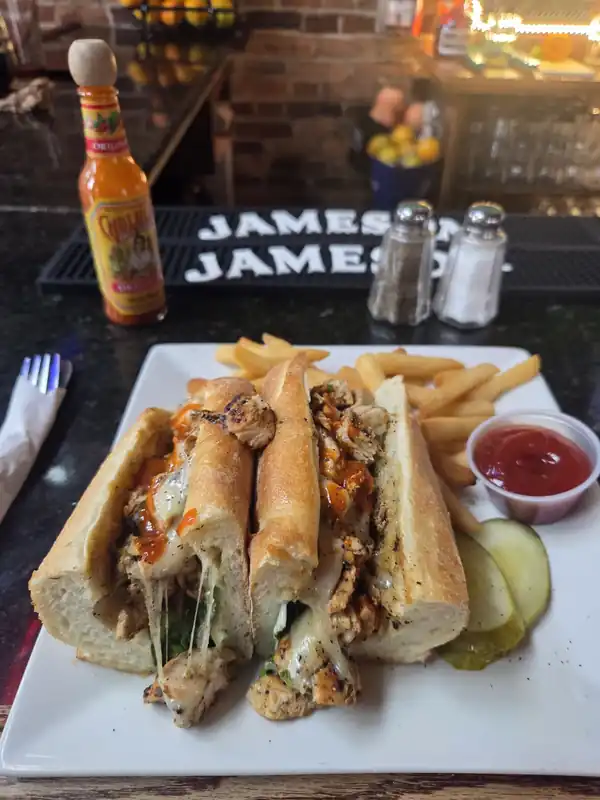 A chicken cheesesteak and fries on the bar top