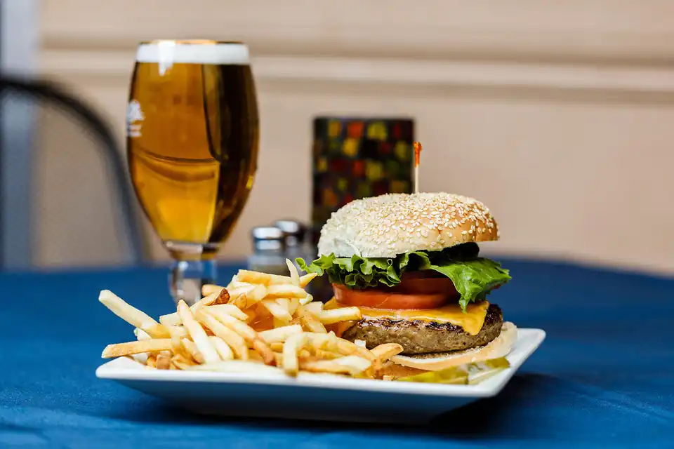 A burger and fries with a pint, on a blue cloth