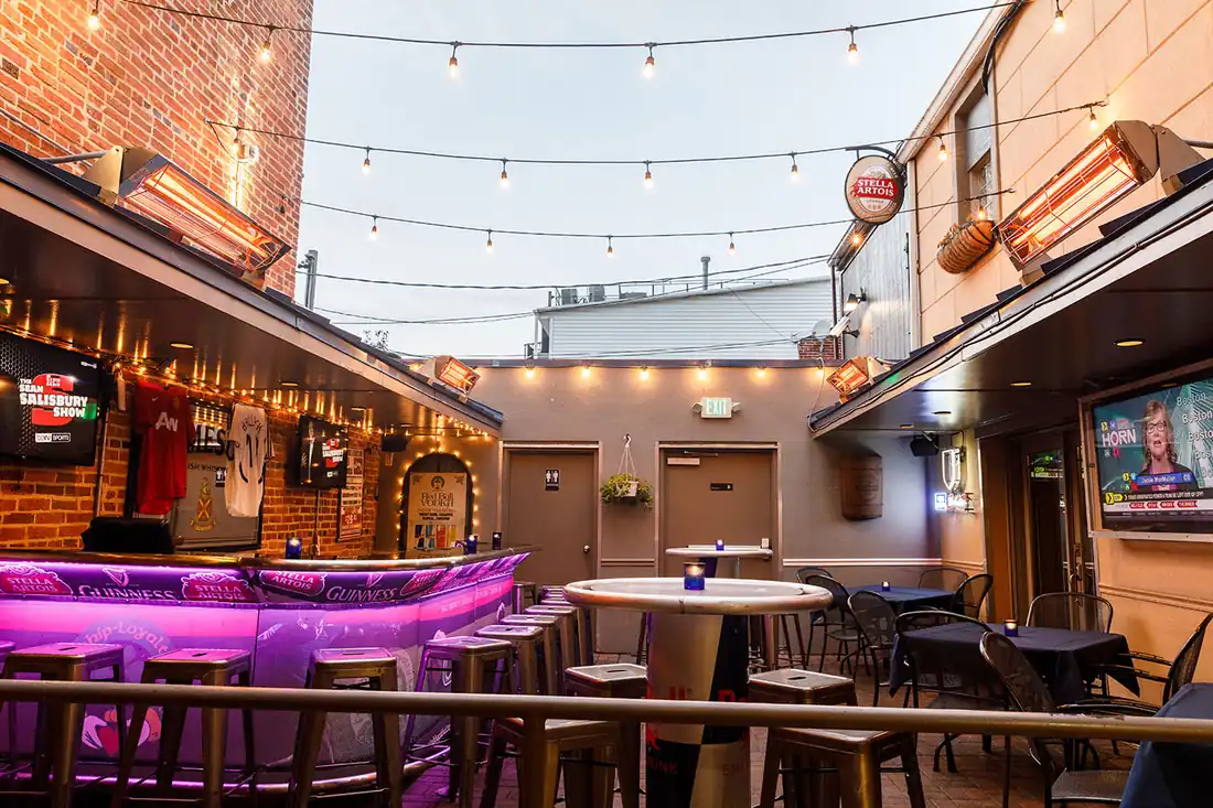 The courtyard bar under strings of lights, lit magenta after dark