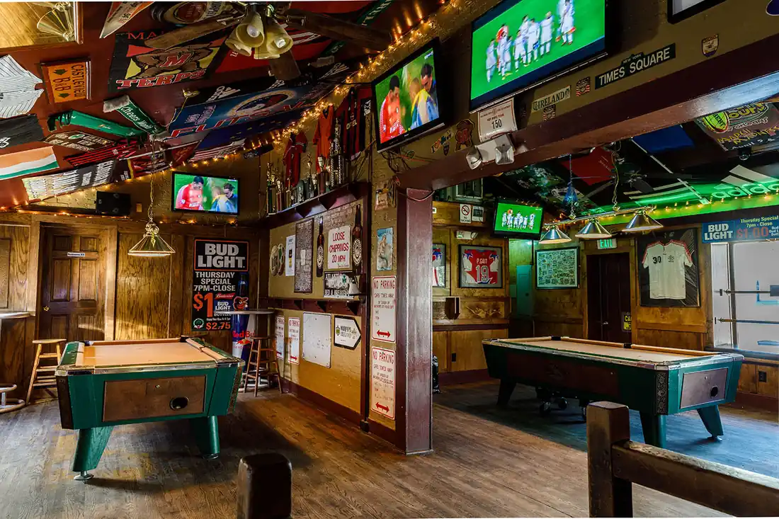 The back room with pool tables under soccer jerseys, scarves and televisions