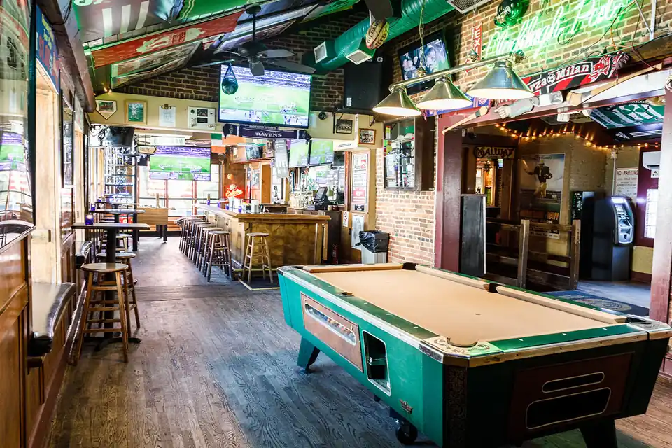 The front room with its pool table, brick wall and televisions over the bar